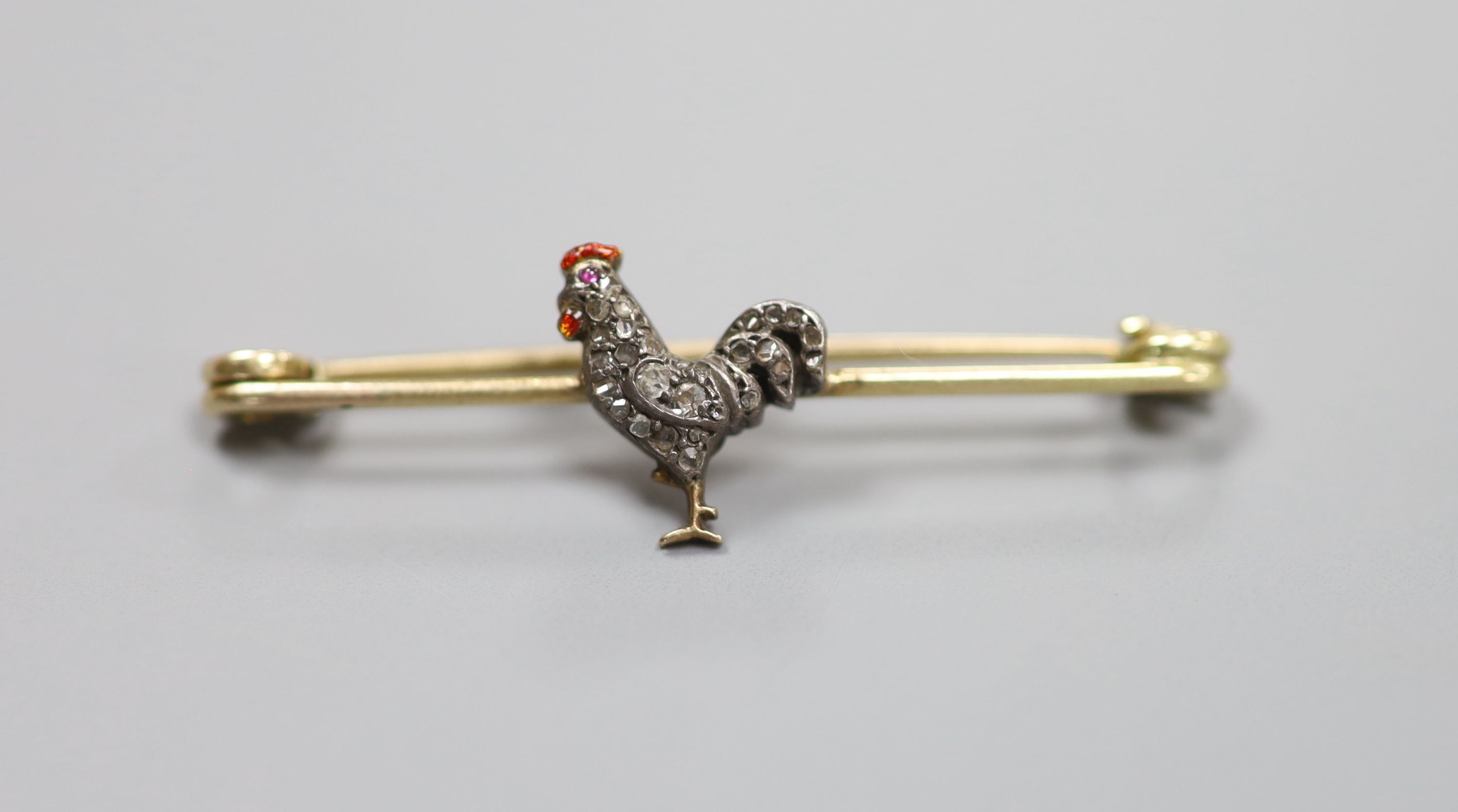 A late Victorian yellow metal, diamond, ruby and enamel set cockerel bar brooch, 45mm, gross 3.3 grams.